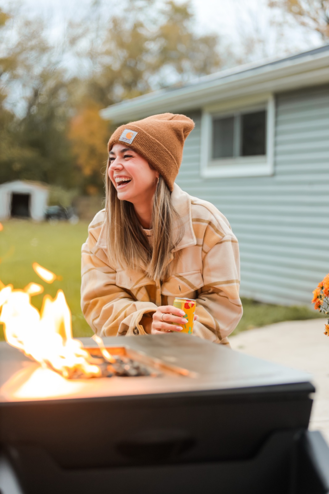A woman laughing beside a fire table