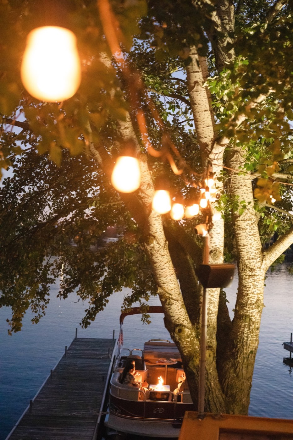 String lights over a dock at dusk