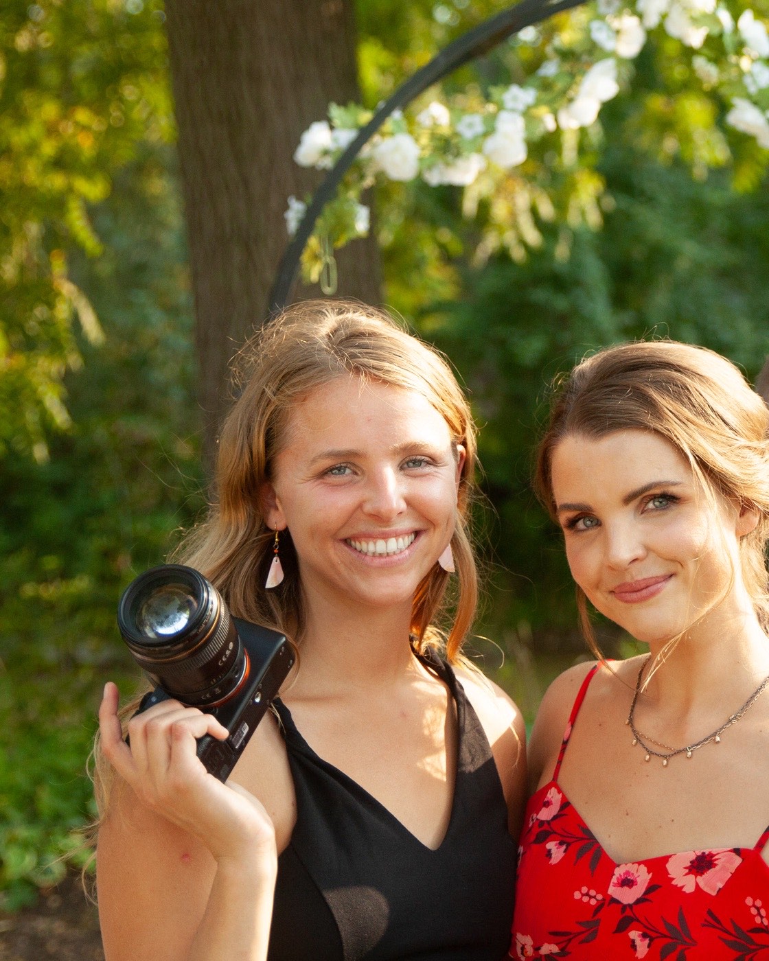 Sabrina and Andrea Boehlke laughing together, cameras in hand, at a wedding venue