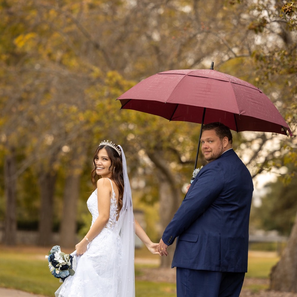A bride holding a red umbrella among vines