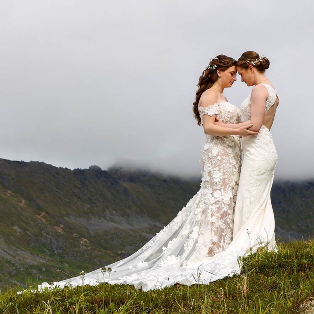 A bride on a hillside above a mountain valley
